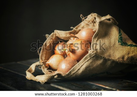 hand hold fresh onion cloth bag isolated on wooden surface