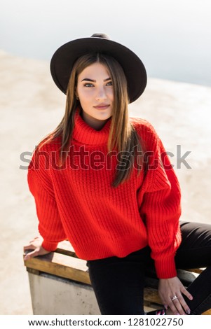 Beautiful woman in black hat sitting on a bench in a city park