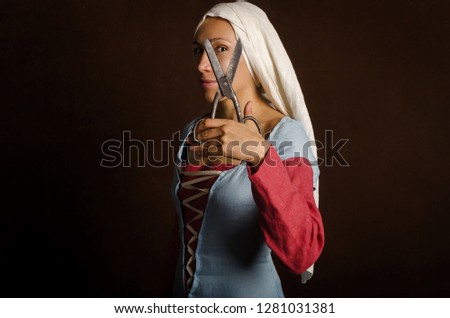 Portrait of a woman (actress) in a medieval dress on a brown stylized background. Woman tailor with ruler and scissors. Hobby. Reenactment of medieval life.