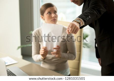 Hand gesture tells youre fired from job for bad work, angry boss showing exit way to incompetent sad employee, dismissing subordinate after paperwork failure, focus on pointing finger, close up view Royalty-Free Stock Photo #1281031501