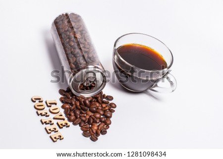 Plastic transparent jar with coffee grains with a straw and a cup of aromatic coffee and the inscription love coffee

