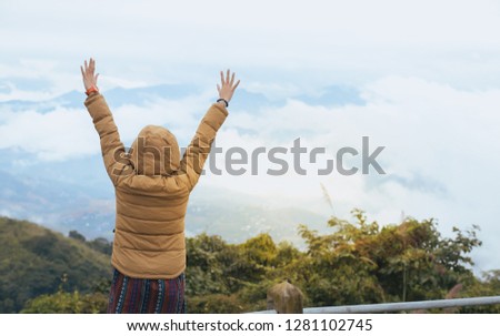 The woman stood facing the arms with a blue mountain mist view.