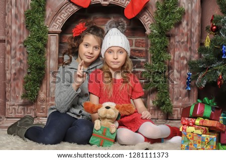 two girls child with presents near the fireplace
