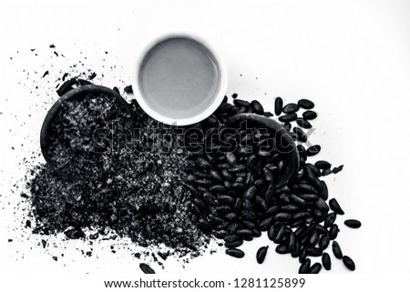 Close up of paste of custard apple seeds in a glass bowl with some powdered seeds and raw dried seeds isolated on white.