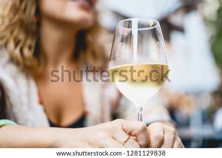 a woman chat in the bar holding a glass of white wine in her hands