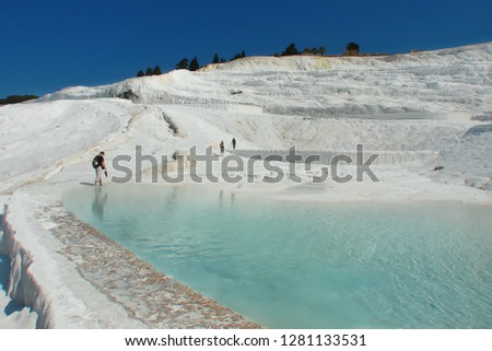 snow-white chalk rock; tourists walk along the edge of a natural pool with the purest mineral water; healing springs, spa resort (Pamukkale, Turkey)