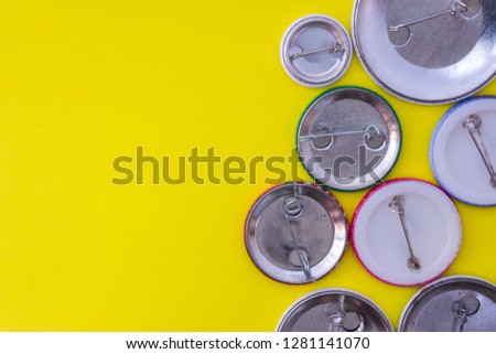 Inverted metal badges with clasps on yellow uniform background view from above with the clear area of half photo for labels, headers. Concept photo for prizes, souvenirs