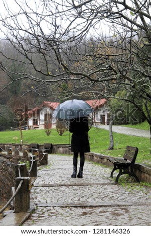 Woman holding umbrellas along the way.