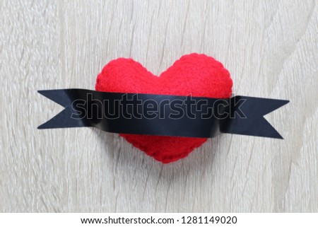 Red heart placed on wooden floor and has a black sticker over it,concept of love and Valentines Day.