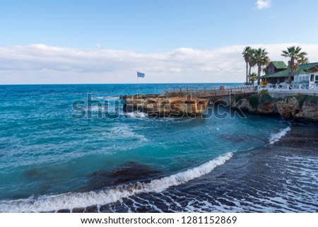 Bay with a withdrawing wave leaving foam stripes behind, cliff and horizon and blue sky in background, picture from near the little village (Limenas Chersonisou) on Crete Island Greece.