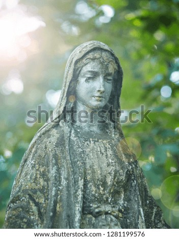 Statue of Mary Mother of God, at autumn tree backgroung. Religious symbol.