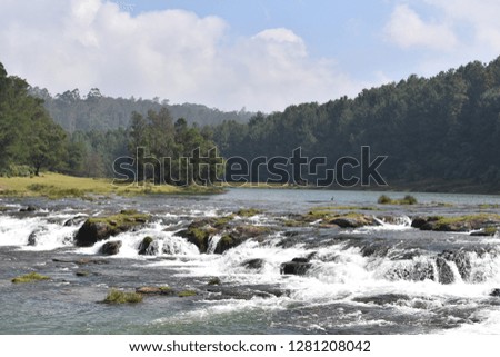 Waterfalls sounded by pine trees and rocks and mountain 