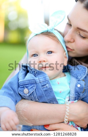 Closeup young caucasian mother kissing little daughter wearing jeans jacket. Concept of motherhood and children.