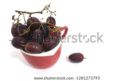 Evening snacks such as grapes are very delicious, some grapes are in a red cup, it seems a wine falls because it is full in the cup. 