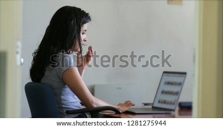 Girl putting her hands in front of her face concerned about what she browsing online. Hispanic girl in front of laptop computer at work