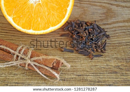 Spices and sliced fresh orange on a wooden table. Ripe orange, Cinnamon sticks and cloves on wooden background, close up.  Royalty-Free Stock Photo #1281278287