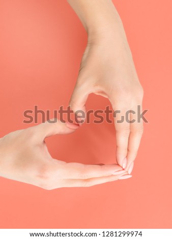 Woman hands making heart sign. On soft red background