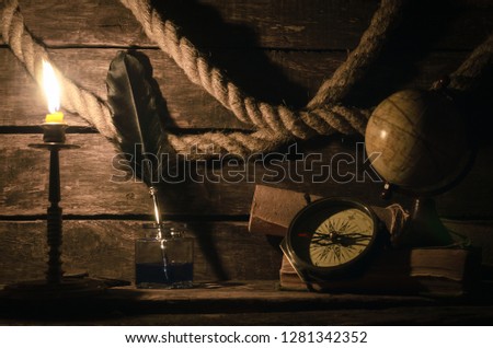 Sea travel background. Adventure background. Globe, compass, mooring rope, scroll map, quill pen in inkpot diary book and burning candle on a wooden captain table.
