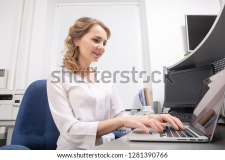Happy smiling girl using laptop for studying in open work place