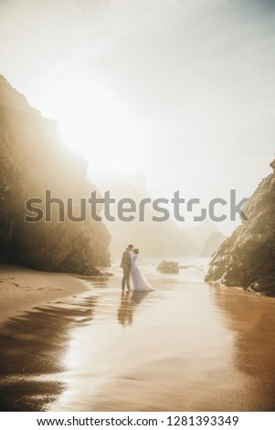 Amazing picture of young couple , bride in long dress with her groom in the ocean