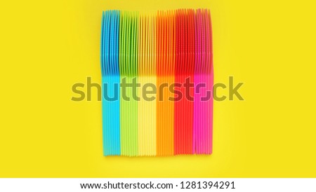 Plastic knives violet, orange, yellow, blue, red isolated on yellow background - bright summer concept for design and banners