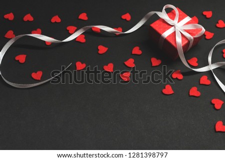 Valentines day background. Red gift box and red hearts on black background.