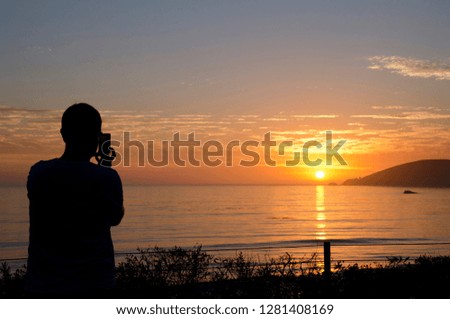 California, Pacific Coast, Pismo Beach. Man taking photo of Pacific Coast sunset.