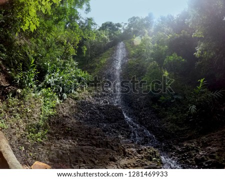 Small and bucolic waterfall surrounded by stones in a magically hidden scenery of a tropical forest.