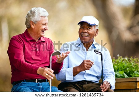 Two senior men sitting together on a golf course.