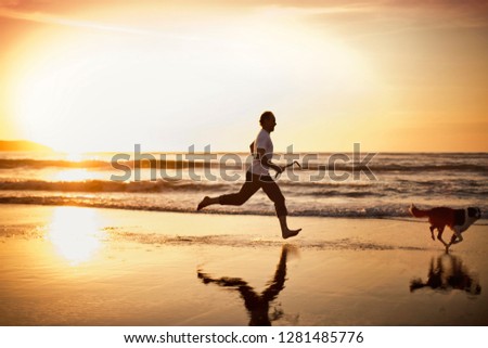Mature man running with his dog on the beach.