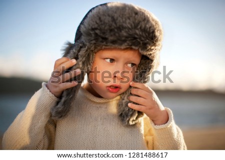 Portrait of a young boy outdoors wearing a fur hat.