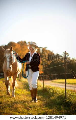 Woman walking horse through pasture.