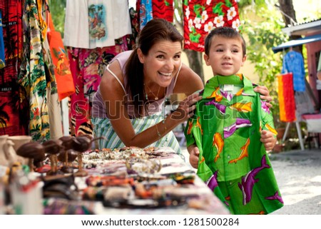 Smiling woman and her son shopping at a market together.