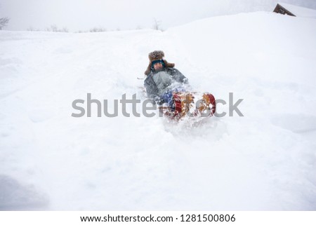 Boy having fun riding a sled in the snow.