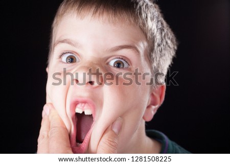 Young boy close up studio shot with green jumper, squashed goofy face.