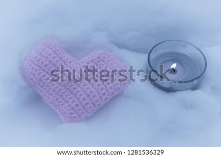 Knitted pink heart and a lighted candle