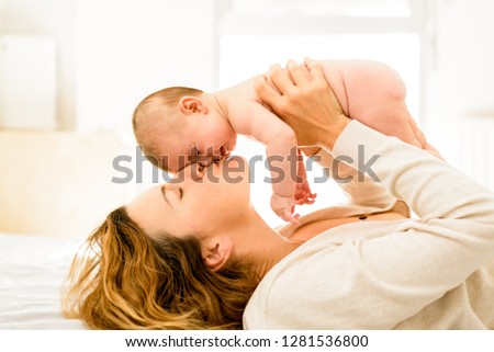 Mom kissing her newly born daughter lovingly, concept of motherhood and happy family life.