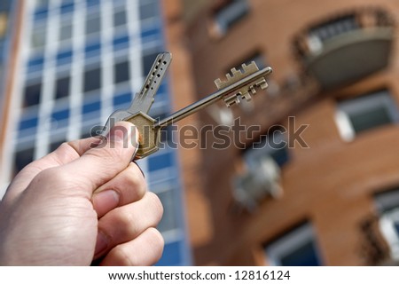 On a background of a modern brick house, hand with keys from an apartment.