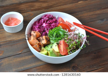 Organic food. Fresh seafood recipe. Fresh salmon poke bowl with rice, fresh red cabbage, avocado, cherry tomatoes, cucumber, radish sprouts on wooden background. Food concept poke bowl