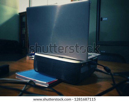 The laptop is connected projector by cable prepare to presentation in meeting room. The laptop on projector. Blue tone and depress feeling are applied.