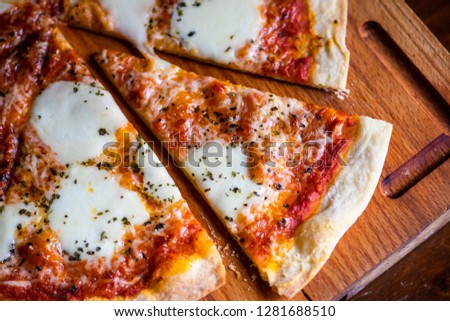 Italian pizza in slices on dark wooden cutting board with copy space