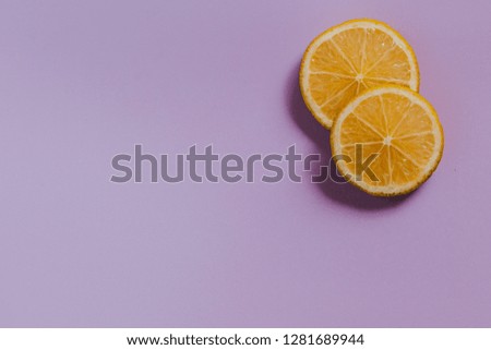 Minimalist layout of orange slices on purple background.