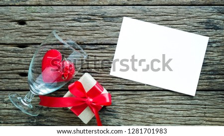 Valentine's Day with red rose with wooden floor, red ribbon, gift box, wedding ring, message