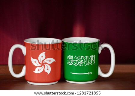 Saudi Arabia and Hong Kong flag on two cups with blurry background