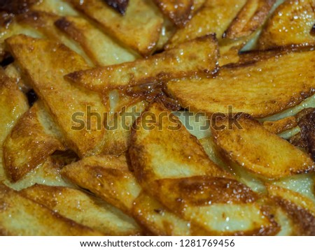 Golden slices of fried potatoes in vegetable oil in a frying pan.