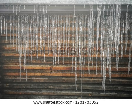 Big icicle on the roof with wooden background