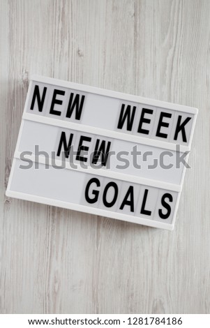 Modern board with text 'New week new goals' over white wooden background, top view. From above, flat lay, overhead. 