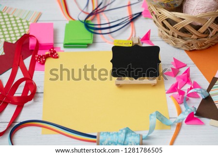Colorful background with various party confetti, paper decoration, flags, stationary, DIY accessories with woman's hands making greeting card. Fat lay top view. Party arrangement