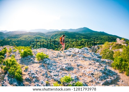 Girl at the top of the mountain. A woman with a backpack walks along a mountain path. Climb to the top. Travel to picturesque places. Tourist against the sky and the sea.