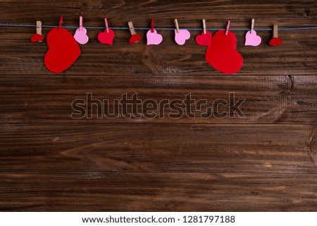 clothespins with red hearts on a ribbon as a border on a brown wooden background with space for text. The concept of Valentine Day, copy space